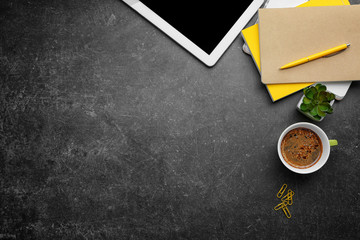 Cup of coffee with office tools on gray background