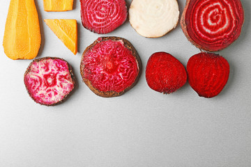 Fresh young sliced beets and carrots on grey background