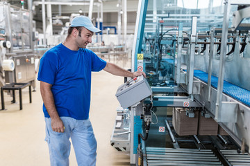 Fototapeta na wymiar Happy smiled worker doing his job on Robotic factory line for processing and quality control in water factory.