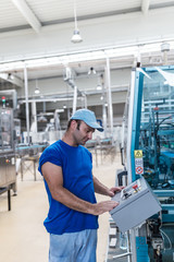 Happy smiled worker doing his job on Robotic factory line for processing and quality control in water factory.