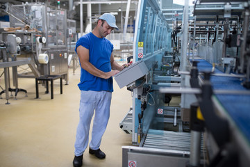 Happy smiled worker doing his job on Robotic factory line for processing and quality control in water factory.