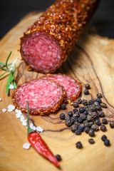 dried salami crusted in ground red pepper on dark background