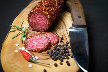 dried salami crusted in ground red pepper on dark background