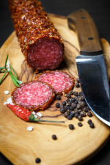 dried salami crusted in ground red pepper on dark background