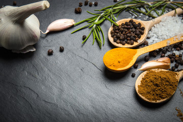 spices and herbs over black stone background, top view with copy space