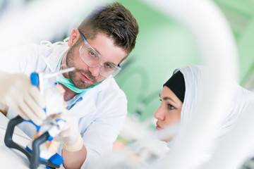 Dental prosthesis, dentures, prosthetics work. Arab students with hijab while working on the denture, false teeth, a study and a table with dental tools