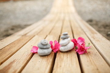 Zen stones spa at sandy beach with tropical pink flowers