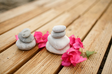 Zen stones spa at sandy beach with tropical pink flowers