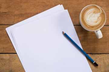 Office desk table with blank paper page, pencil and cup of coffee.Top view with copy space.Office...