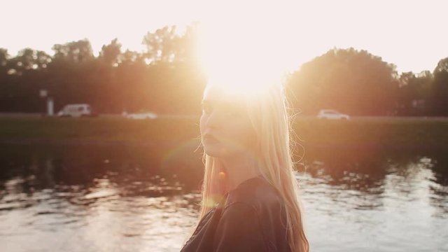 Young girl posing on the gren grass near the river at sunset