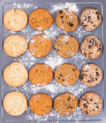 Variety of baked cookies with flour on baking sheet ready to eat