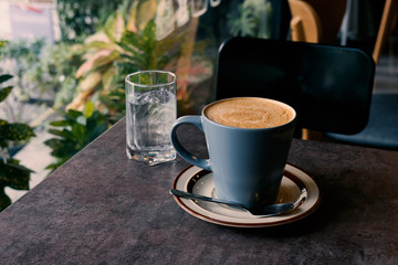 hot fresh coffee blue cup on table chair and glass of water surrounding tree / hot fresh coffee blue cup