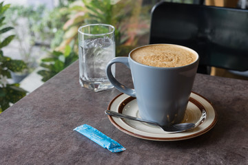 hot fresh coffee blue cup on table chair sugar and glass of water surrounding tree / hot fresh coffee blue cup