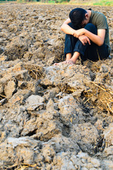 Frustrated and sad young man sitting in barren ground