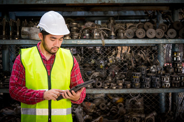 Asian worker using tablet for work in factory warehouse car parts.