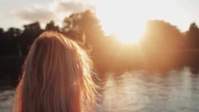 Young girl posing on the gren grass near the river at sunset
