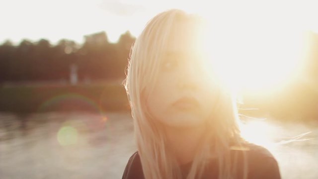 Young girl posing on the gren grass near the river at sunset