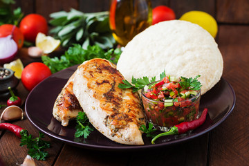 Grilled chicken breast with fresh tomato salsa and pita.