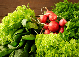 Large bunch of fresh Organic vegetables, radish, spinach, salad and greens on old wooden table, closeup