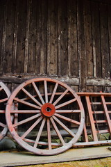 Obraz premium Wooden wheels leaning onto wooden house