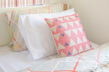 Pink graphic pattern pillow setting on bed with girl style bedroom interior