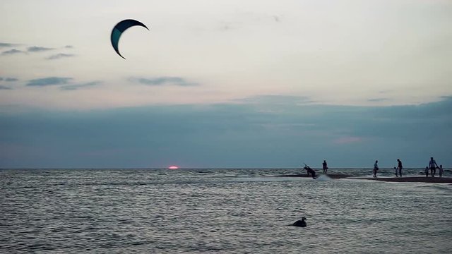 Kitesurfing. Silhouettes of two surfers riding on boards on the surface of waves at sunset. Azov sea. HD