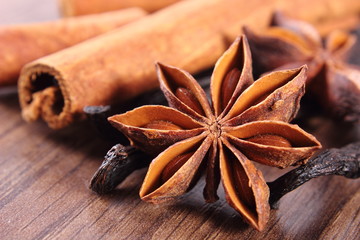 Closeup of star anise, fragrant vanilla and cinnamon on wooden surface plank