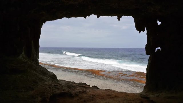 Wave breaking on the seashore seen from a cavern on the coast, Rurutu island, Pacific ocean, Austral archipelago, French Polynesia

