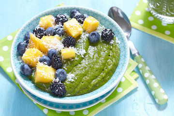 Breakfast green smoothie bowl topped with fruits