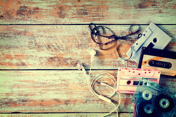 Top view (above) shot of retro tape cassette with earphone on wood table - vintage color effect styles.
