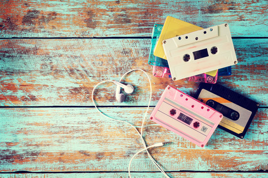 Top view (above) shot of retro tape cassette with earphone heart shape on wood table. Love music concept - vintage color effect styles