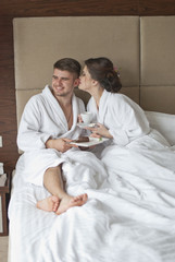 Beautiful young couple having breakfast in bed. 