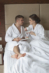 Beautiful young couple having breakfast in bed. 