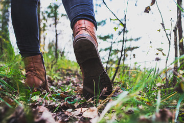 Female legs shod in Hiking boots on the forest background