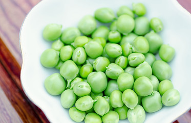 Fresh green peas on white plate, close-up