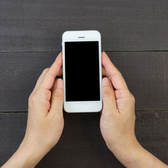Woman hand holding and using mobile,cell phone,smart phone with isolated screen on wooden table or wooden floor for background.