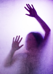 Trapped woman, back lit silhouette of hands behind matte glass