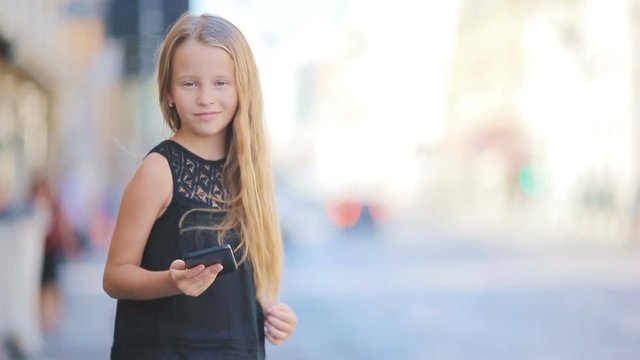 Adorable little girl with smart phone outdoors in european city, Rome, Italy