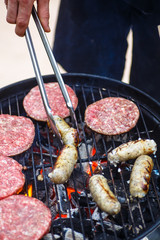 Burgers and sausages for hot dogs are roasting on the grill.