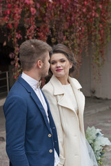 Just married loving couple in wedding dress and suit outdoor in city setting against wall. Happy bride and groom laughing and kissing. Romantic Married young family. 