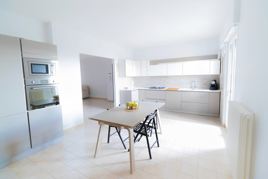 modern, bright, clean, kitchen interior with stainless steel appliances and friut apple on table in a luxury house