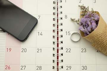ring purple flower and mobile phone on calendar background