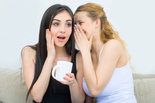 Two happy friends talking and drinking coffee or tea