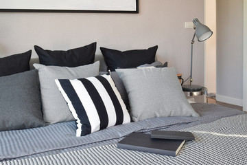 stylish bedroom interior design with black patterned pillows on bed and decorative table lamp.