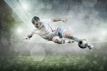 Soccer player with ball in action at stadium under rain.