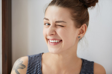 Nice close-up portrait of young European hipster girl with bunch of brown hair and tattoo. Happy...
