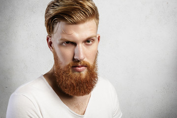 Close-up portrait of young Caucasian man with long ginger beard and trendy hairstyle. Young hipster...