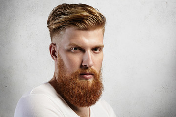 Sideways portrait of natural blond Caucasian man on white background. Bearded hipster with clean...