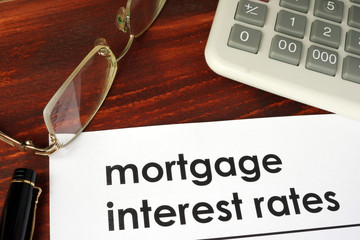 Paper with words mortgage interest rates on a wooden background.