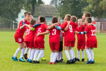 Fotobehang kids soccer team in huddle © Dusan Kostic